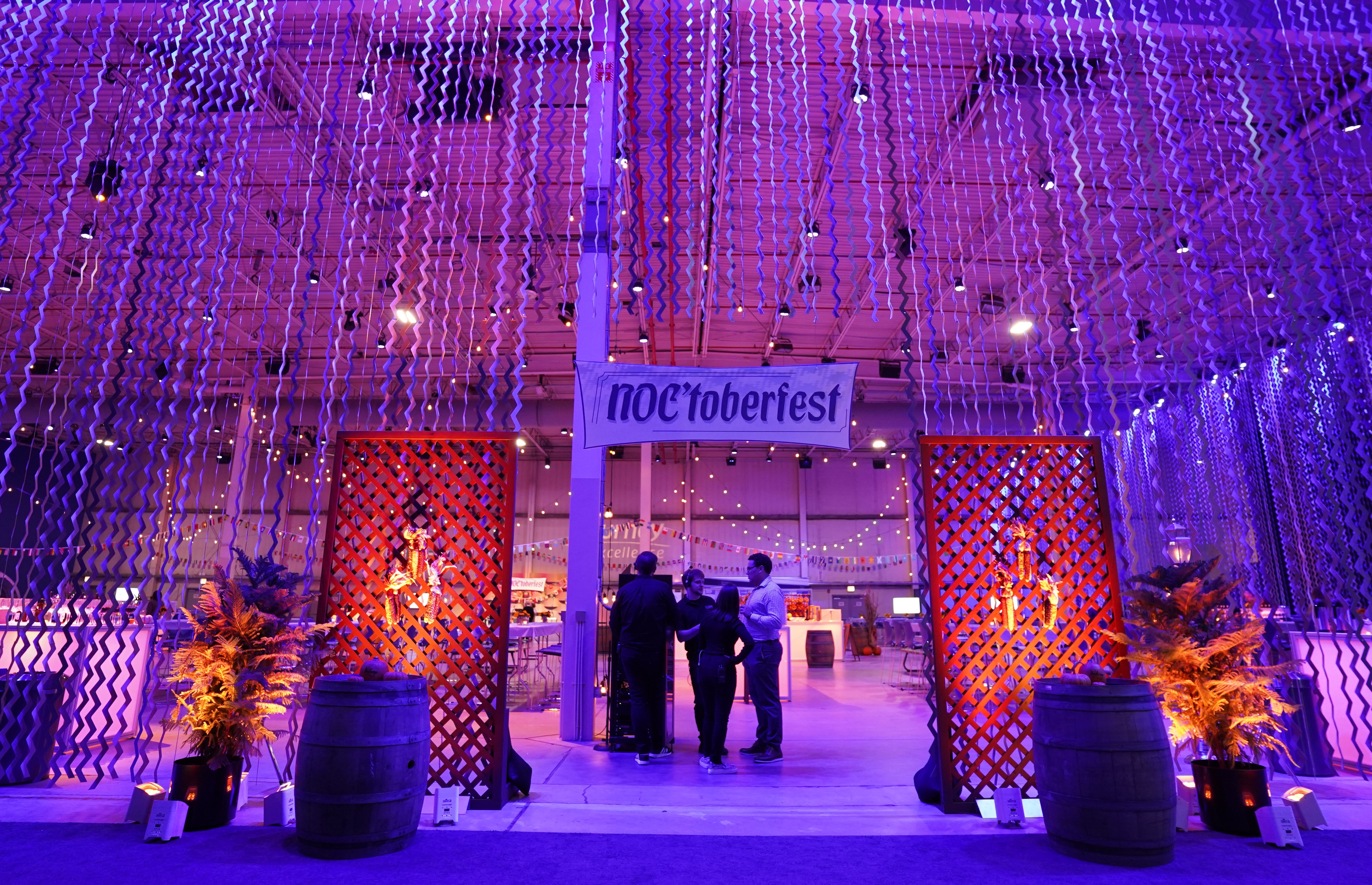 A group of people standing at event with purple and orange lighting.